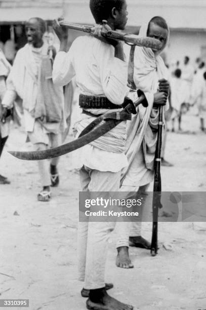 An Abyssinian peasant warrior, carrying his rifle round his neck and a huge sword slung around his waist at Harer before leaving for the southern...