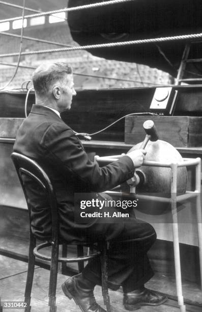Joe Palmer, one of the time-keepers for the fight between Peterson and Harvey at Wembley, London, trying out the bell at the ringside.