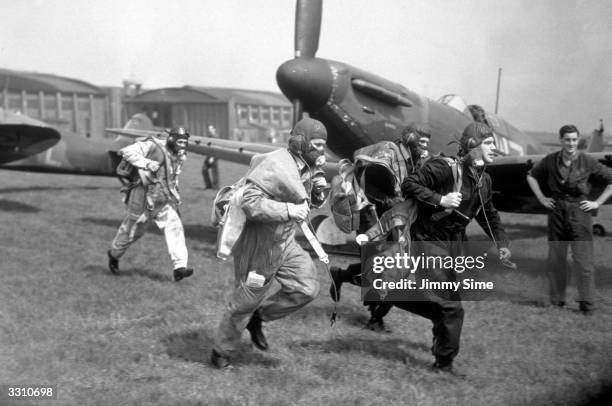 Pilots of No 19 Squadron, Royal Air Force Fighter Command scramble to their wooden, two-blade, fixed-pitch propellered Supermarine Spitfire MkI...