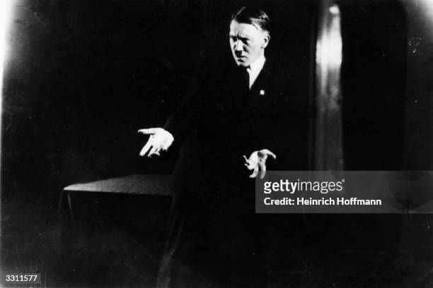 Adolf Hitler , leader of the National Socialist German Workers' Party , strikes a pose for photographer Heinrich Hoffmann whilst listening to a...
