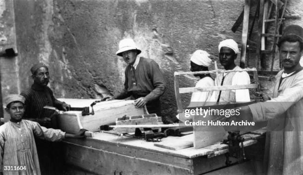 English egyptologist Howard Carter supervising carpenters preparing to re-seal Tutankhamun's tomb.