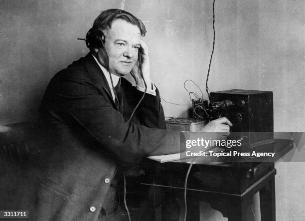 Herbert Hoover , Republican Party candidate for the Presidency of the United States of America, listening to a one valve radio set.