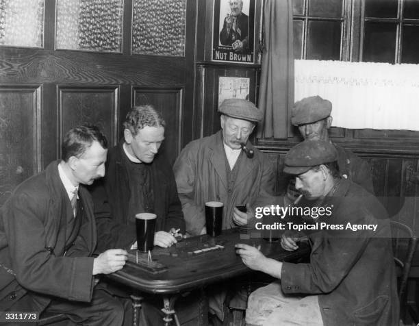 The Reverend E Scarlett enjoying beer and dominoes with some of his parishioners in their local pub in Chessington.