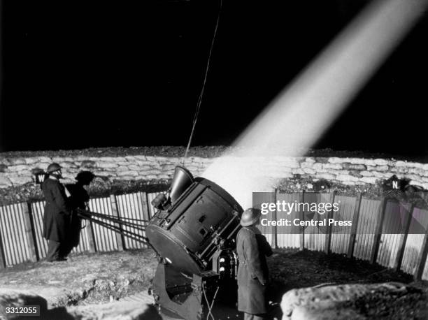 Projector, operating from its sunken sandbagged emplacement, at a searchlight station in the London area.