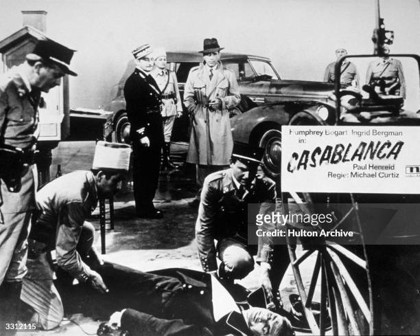 Claude Rains and Humphrey Bogart view the body of Conrad Veidt on a poster advertising the film 'Casablanca', directed by Michael Curtiz for Warner...