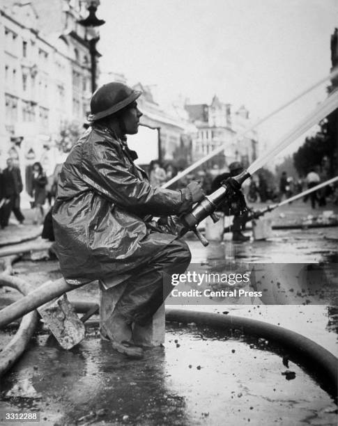 Fireman attempts to check the flames from a gas explosion, after an air raid in Central London the previous night.