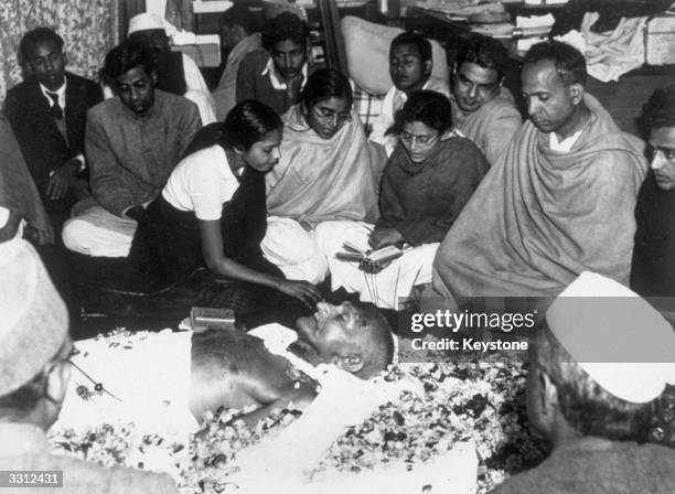 The niece of Mahatma Gandhi places flower petals on his brow as he lies in state at Birla House, New Delhi, after his assassination. Immediately...