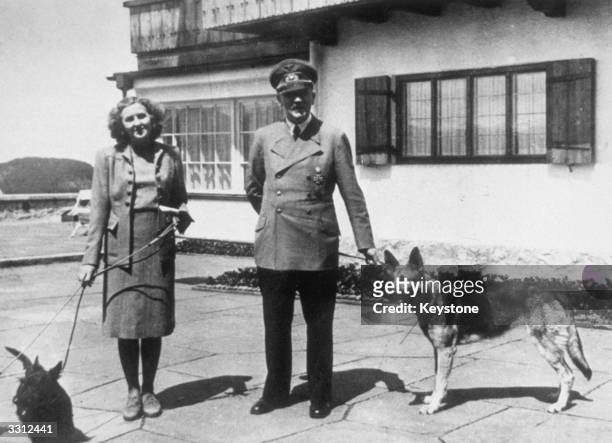 Hitler with Eva Braun, his supposed wife, photographed with their dogs at Berchtesgaden. The picture is from a photograph album belonging to Eva...