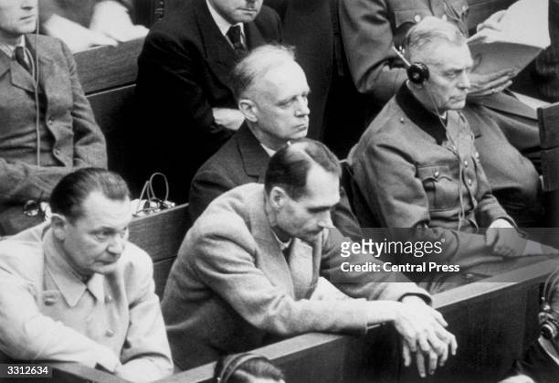 Rudolf Hess rests his hands over the bench during the Nuremberg war trials as he listens to the evidence. With him are Joachim von Ribbentrop,...