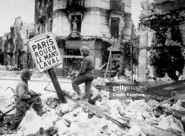 British infantry soldiers searching the wrecked streets of Caen for snipers.