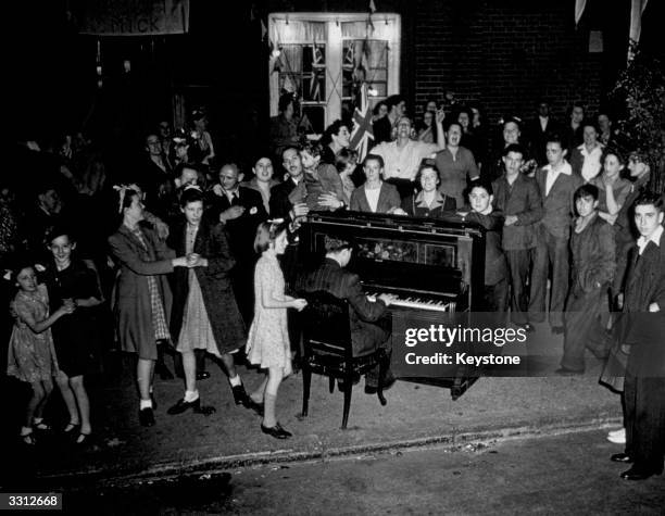 Dancing through the night at the Peabody Buildings, Hammersmith, following news of Japan's surrender. A piano carried out into the street provided...