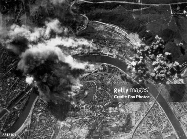 Smoke from fires and explosions rises upwards from the marshalling yards at Liege, a main target of the bombs of the B-17 Flying Fortresses of the US...