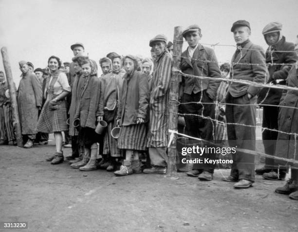 Starving internees at Belsen concentration camp waiting at the cook house gate for their rations of potato soup.