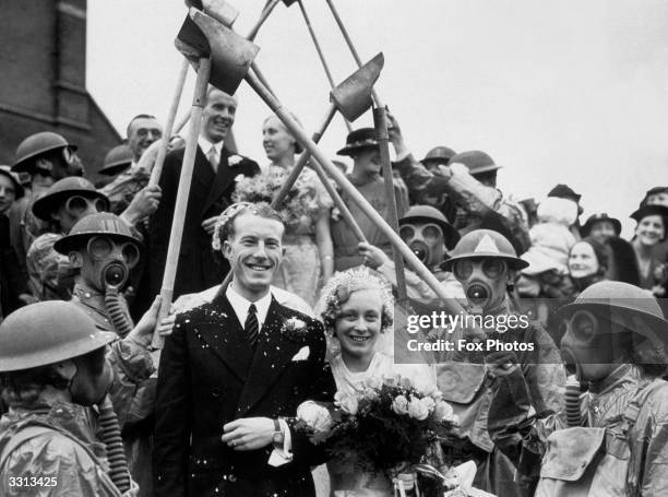 Air Raid Precautions secretary Dorothy Treacher and ARP assistant W G Clemens, leaving their wedding under an archway of incendiary bomb scoops, held...