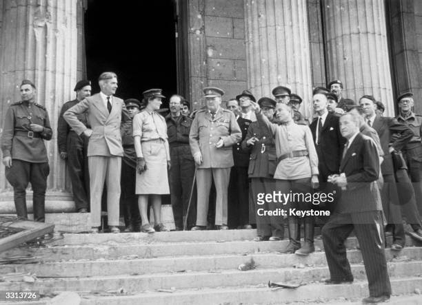 Winston Churchill on the steps of the Chancellery, Berlin. On the left is Anthony Eden, and in the centre is Mary Churchill. A Russian officer points...
