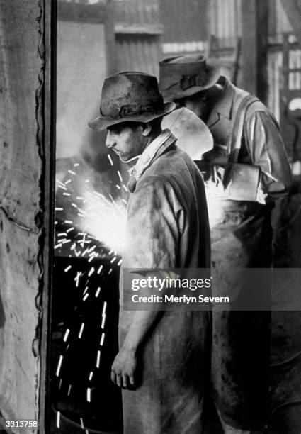 An Indian assistant of a white welder in a sugar factory in South Africa. Skilled trades were mainly banned to all Indians and they were not allowed...