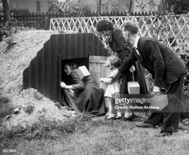 Family entering their dug out in the garden on hearing the air raid warning.