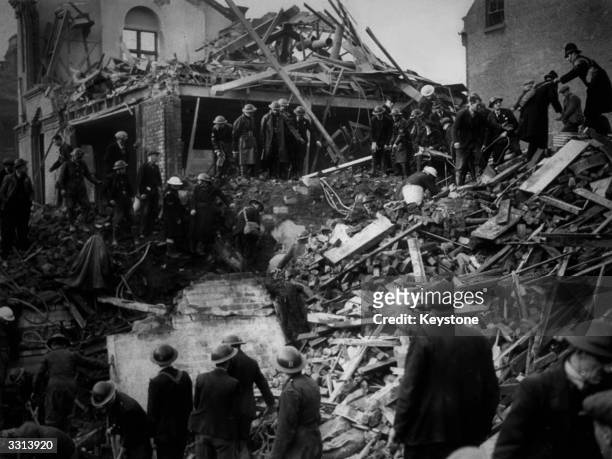 Rescue workers and police clamber over the wreckage of a junior school in Liverpool, bombed during a German air raid.
