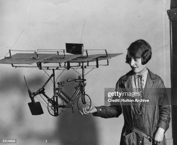 Woman holding a model of a pedal cycle, fitted with wings, which was on exhibition at Central Hall, Westminster, London.