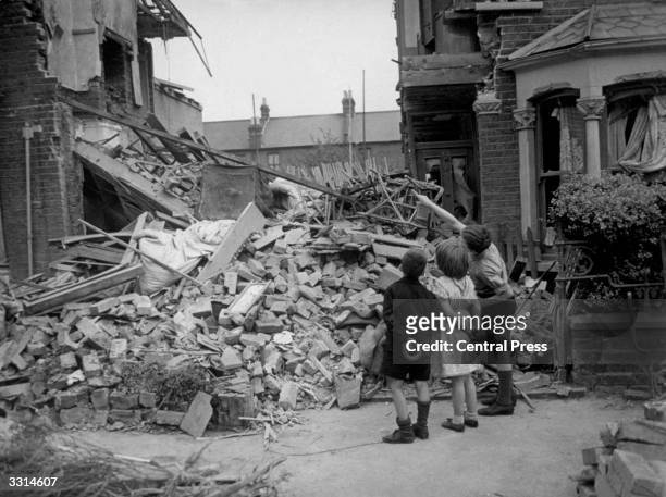 Homeless boy points out his bedroom to his friends, after his home had been wrecked during a random bombing raid in an eastern suburb of London.
