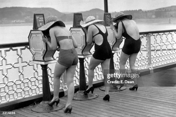 Holidaymakers view 'What The Butler Saw' picture peep shows on the pier at Llandudno, North Wales.