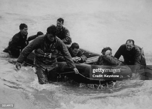 Survivors from a landing craft which sank off Omaha Beach, Normandy, come safely ashore on a life raft during the Normandy Landings. Photo: PFC...