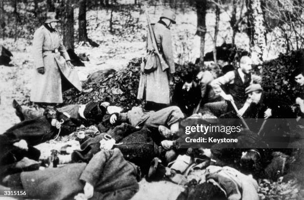 Nazi soldiers supervise the burial of slaughtered Polish Jews into a giant pit, in this photograph which was smuggled out of Germany into America.