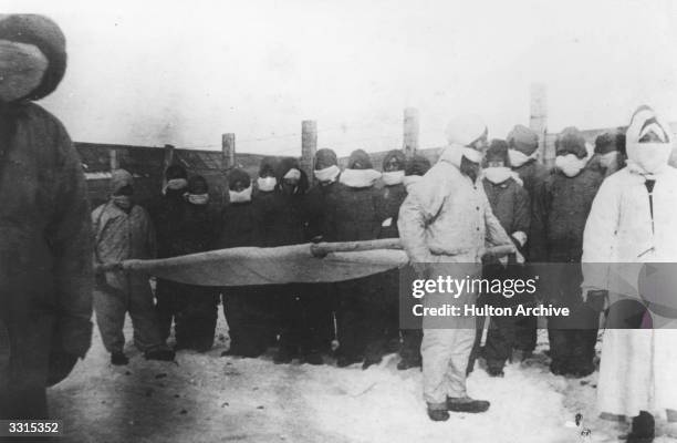 Stretcher bearers prepare to move the dead during a plague in Manchuria.