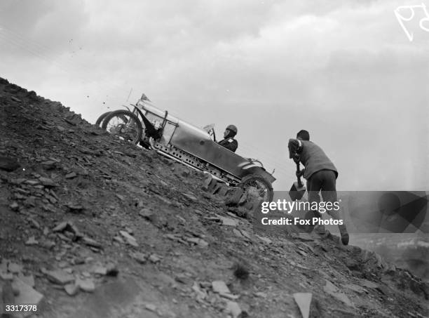 Supporter takes a large mallet to help a competing driver up a steep, shale-covered slope in hill climbing event at Freak Hill near Bradford,...