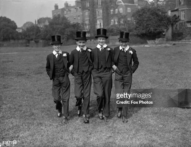 Four young boys in their Harrow school uniform sporting toppers and buttonholes.