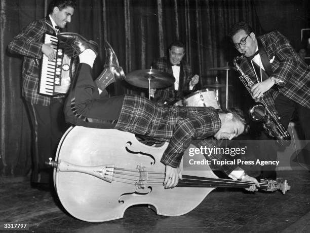 Bill Haley And His Comets rehearsing at the Dominion Theatre, London. Bass player Al Rex plays his double bass while lying on it.