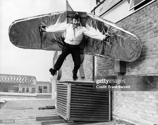 Stuntman trying out his balsa wood wings on the roof of a supermarket in preparation for his attempt to fly across the River Nene at Peterborough.