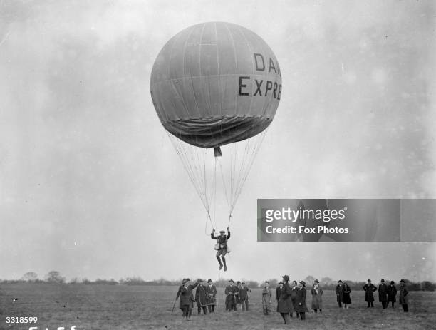 Balloon jumping at Stag Lane Aerodrome. The participant is suspended in a harness under the balloon which appears to be sponsored by the Daily...