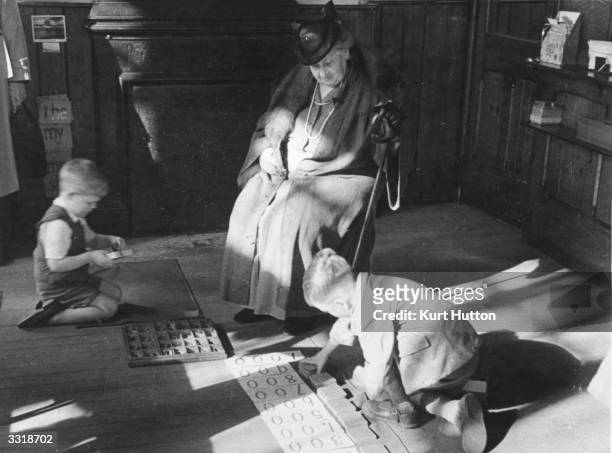 Italian educationist and founder of the Montessori Schools, Maria Montessori , watching a couple of boys working in a classroom in Acton, London....