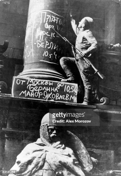 Soviet soldier putting his signature on a column of the Reichstag, Germany. The words over the statue show that a Major Iakovlev fought all his way...