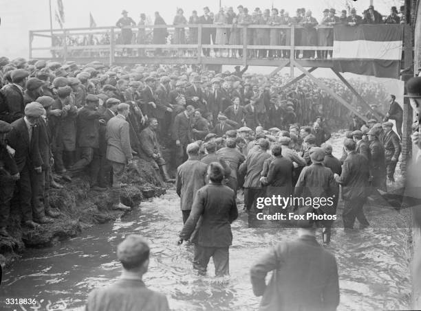 Crowds watch the annual Shrovetide football game, which is 'kicked - off' in the stream which runs through the Derbyshire town of Ashbourne.