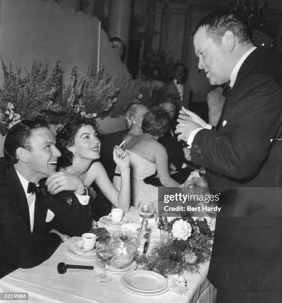 Orson Welles talks to husband and wife Frank Sinatra and Ava Gardner at a charity function at the Empress Club, London, organised by the Variety Club...