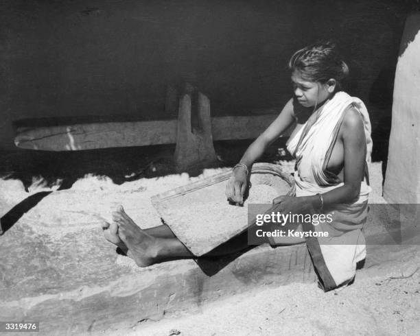 Santhal woman cleaning rice on a doorstep. Cal TV Film Prod Centre