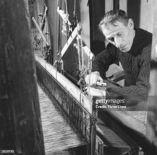 Weaver at work at a loom on the Aran Islands in County Galway. The woven cloth is wound on under his forearms.