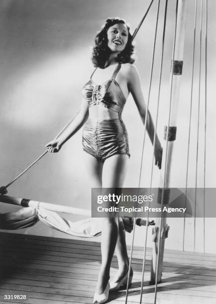 Hazel Court models the latest British fashions in beachwear. Hazel wears a one-piece swimsuit by Martin White with a bare mid-riff in sea green satin...
