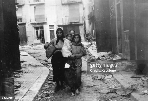 Women and children who fled when the Spanish Nationalist troops started bombarding Tortosa, returning to their home to find it in ruins, during the...