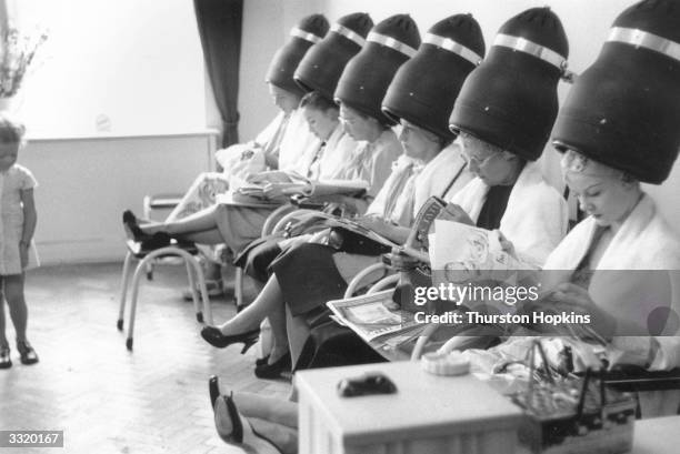 Six women, with Gloria Nord , star of Tom Arnold's Ice Circus in Brighton, under the driers at the hairdressers. Original Publication: Picture Post -...