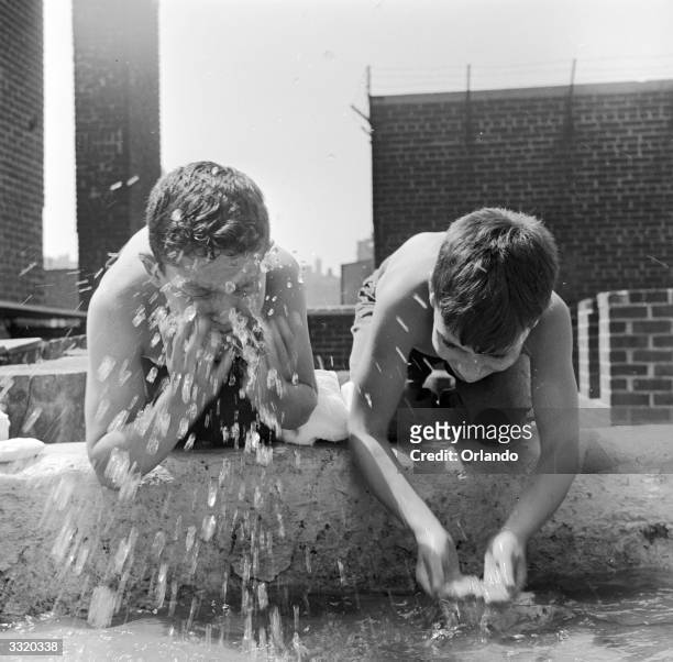 Two campers from the Madison Square Boys Club wash for breakfast at their roof top city summer camp in New York.