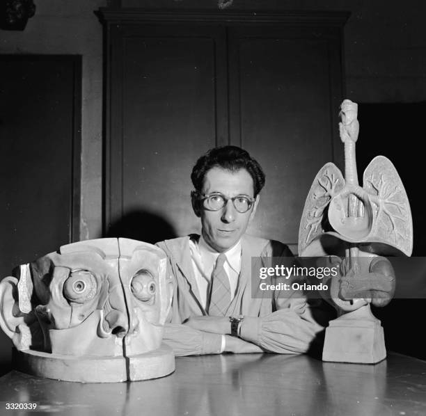 Medical sculptor Abram Belskie of New York Medical College and Flower and Fifth Avenue Hospitals with two of his creations, a larger than life head...