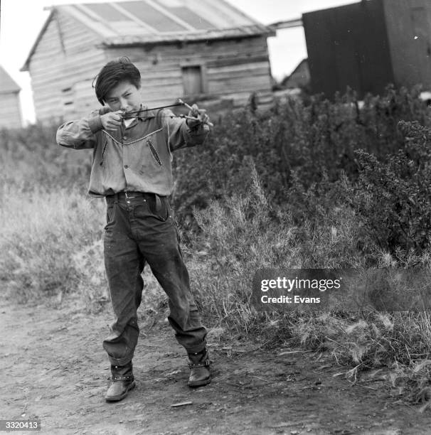 Teenage boy aims his 'sling shot' catapult in an Alaskan village.