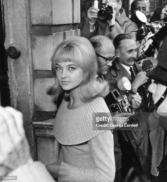 Mandy Rice-Davies, Welsh born model and showgirl, surrounded by press photographers during Stephen Ward's court case in the Profumo affair.