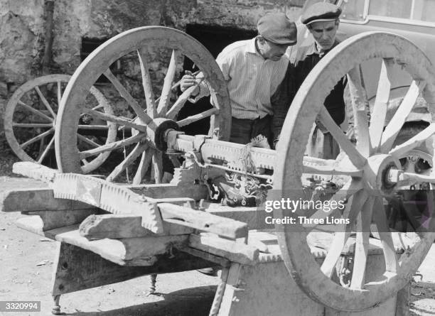 Two men inspect the well-constructed undercarriage of a small cart, which fares better on the mountain roads than most modern vehicles.