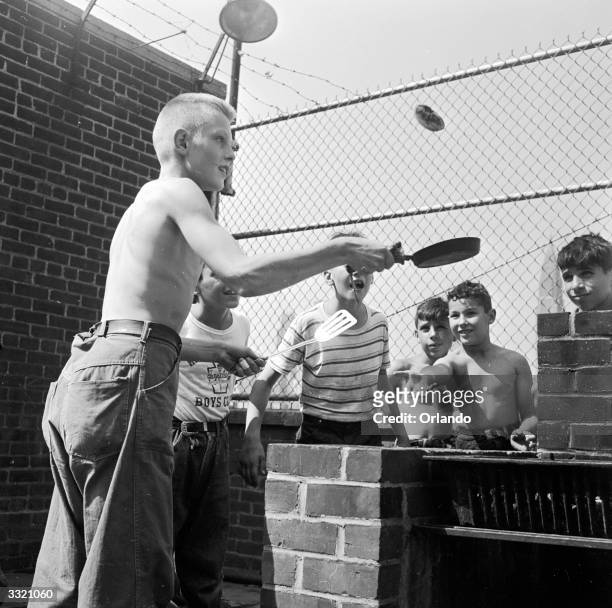 Youth at the Madison Square Boys Club roof top summer camp in New York flips pancakes for an admiring audience.