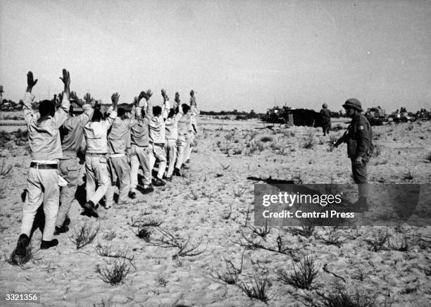 Egyptian prisoners of war holding their hands aloft after being rounded up by Israeli forces in the Sinai desert following the Six-Day War .