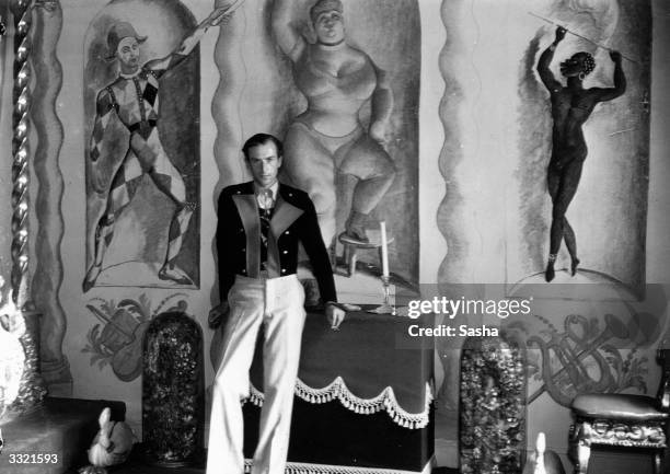 English photographer and designer Sir Cecil Beaton in the 'circus room' at his home 'Ashcombe' in Wiltshire. The murals were by Pavel Tchelitchew,...